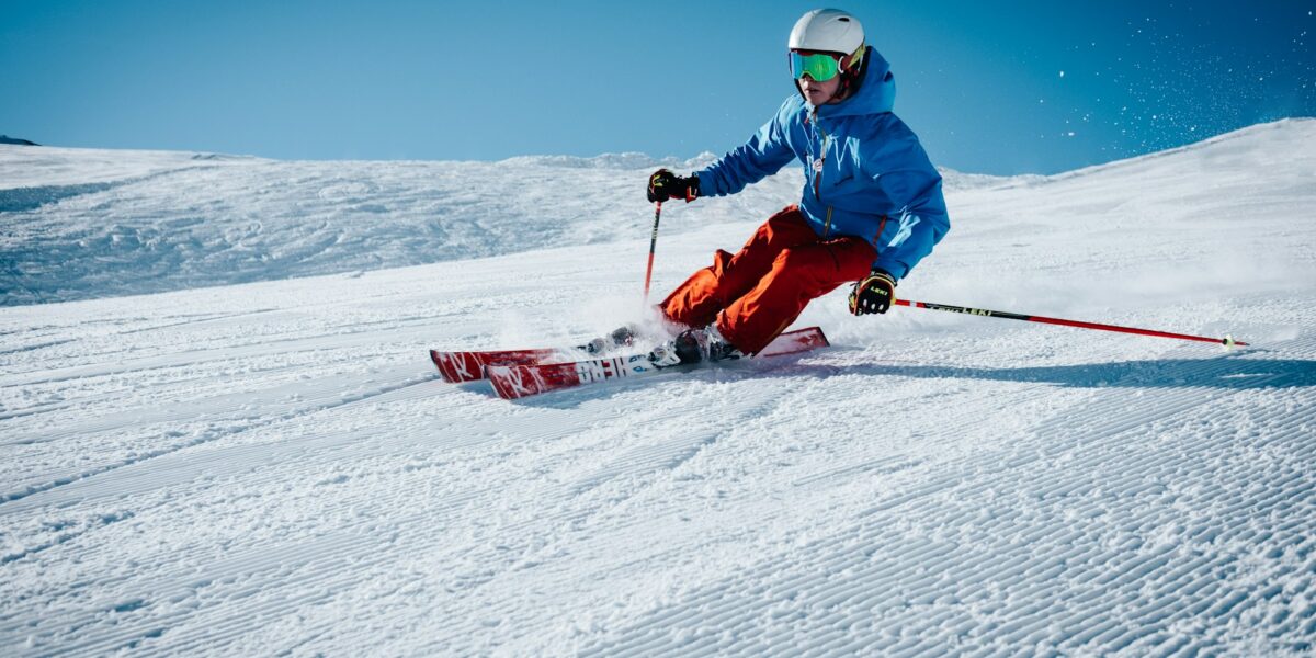 Skier carving on a groomed slope with clear blue skies.