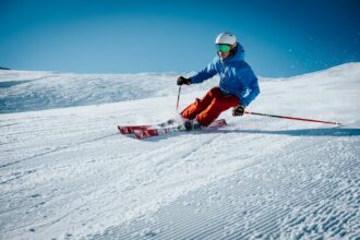 Skier carving on a groomed slope with clear blue skies.