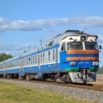 Blue and orange Latvian train on countryside tracks.