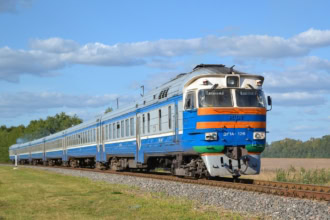 Blue and orange Latvian train on countryside tracks.