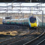 Avanti West Coast train travelling on curved tracks under overhead power lines in the UK.