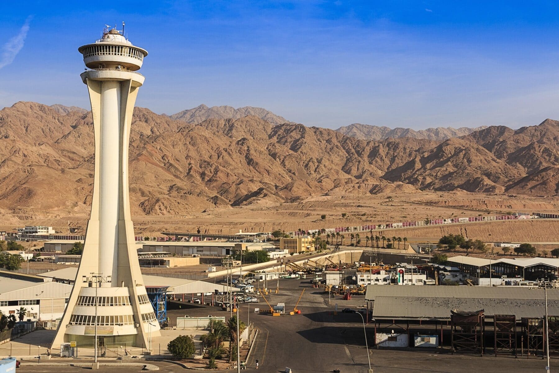 Control tower at King Hussein International Airport in Aqaba, Jordan, set against desert mountains and clear blue sky.