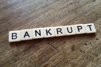 Scrabble tiles spelling the word โBANKRUPTโ on a wooden table