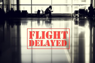 Passenger sitting in an airport terminal during a flight delay with large red “Flight Delayed” sign overlay.