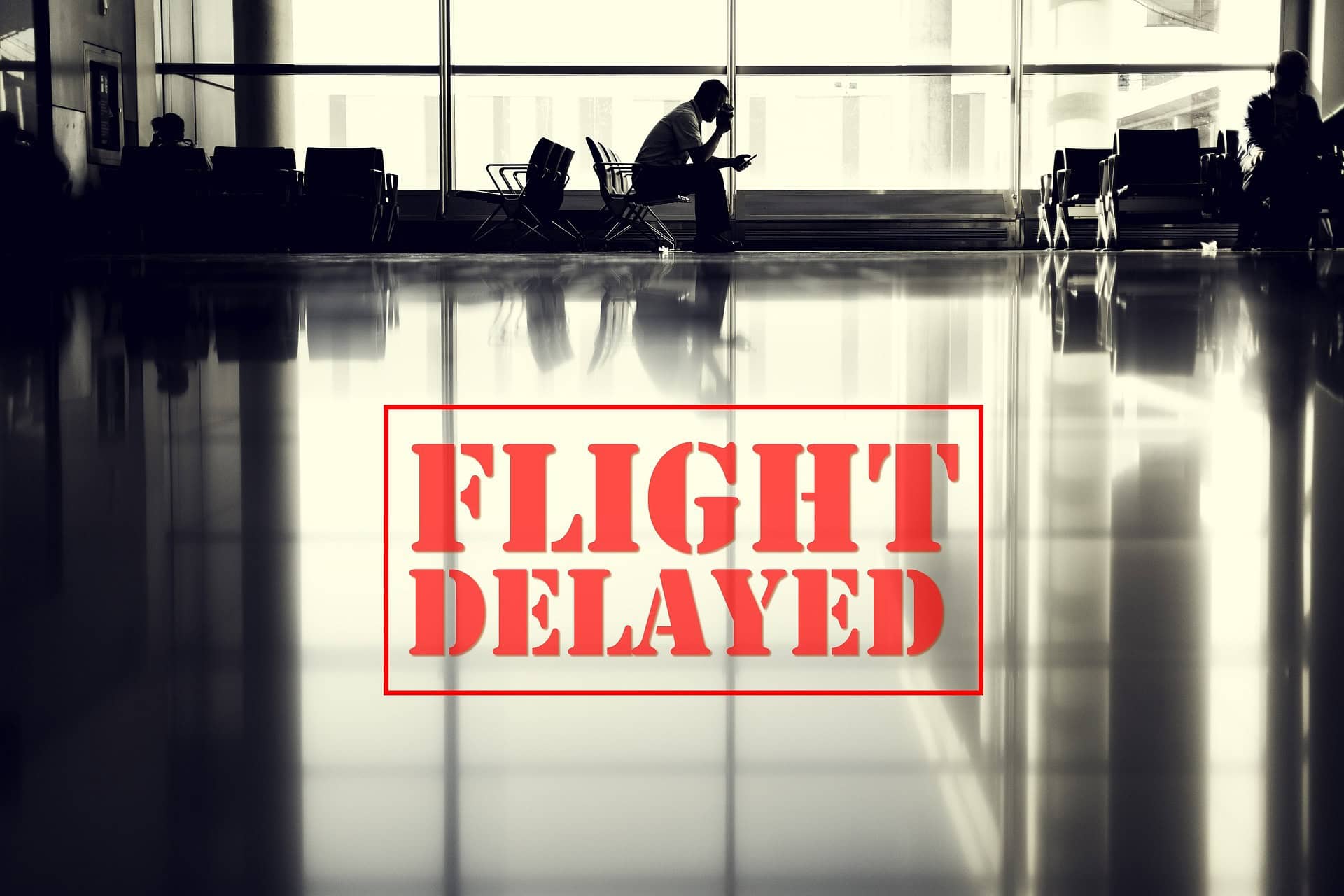 Passenger sitting in an airport terminal during a flight delay with large red “Flight Delayed” sign overlay.