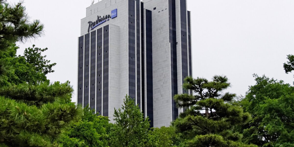 Radisson Blu hotel surrounded by green trees.