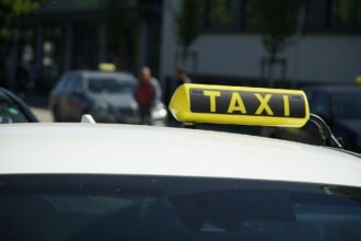 ellow taxi sign on top of a white car in a UK city street