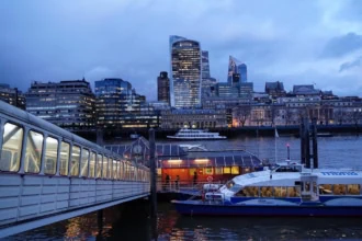 Uber Boat by Thames Clippers vessel docked at Tower Pier with London skyline at dusk