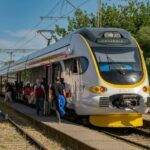 Croatian regional train boarding passengers at a station platform under clear blue skies Title: Croatian regional train at station