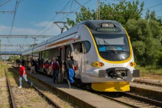 Croatian regional train boarding passengers at a station platform under clear blue skies Title: Croatian regional train at station