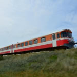Danish regional train in orange and white livery passing through open countryside