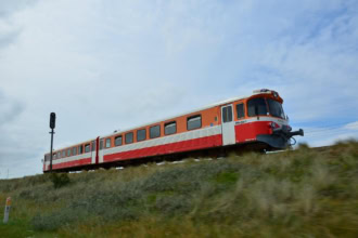 Danish regional train in orange and white livery passing through open countryside