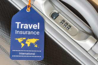 Blue luggage tag reading โTravel Insurance Internationalโ attached to a silver suitcase