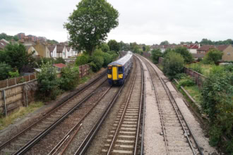 Southeastern train on suburban UK railway tracks surrounded by trees and houses