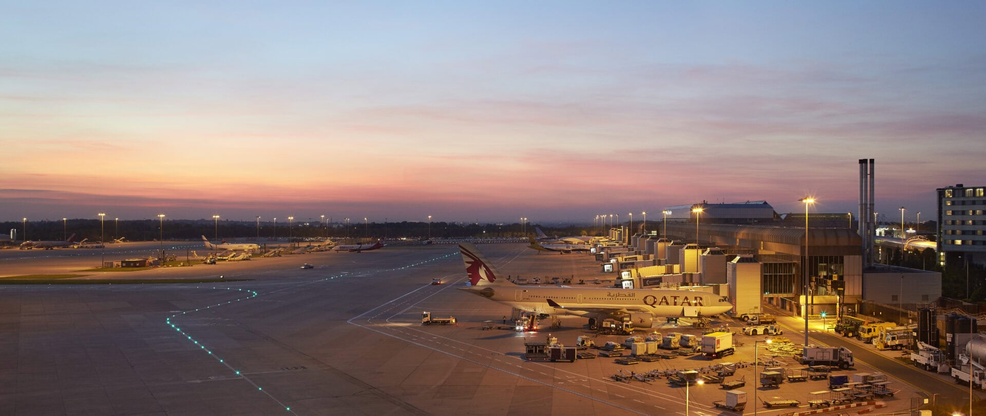 Manchester Airport Terminal 2 apron at sunset with Qatar Airways aircraft parked at gates