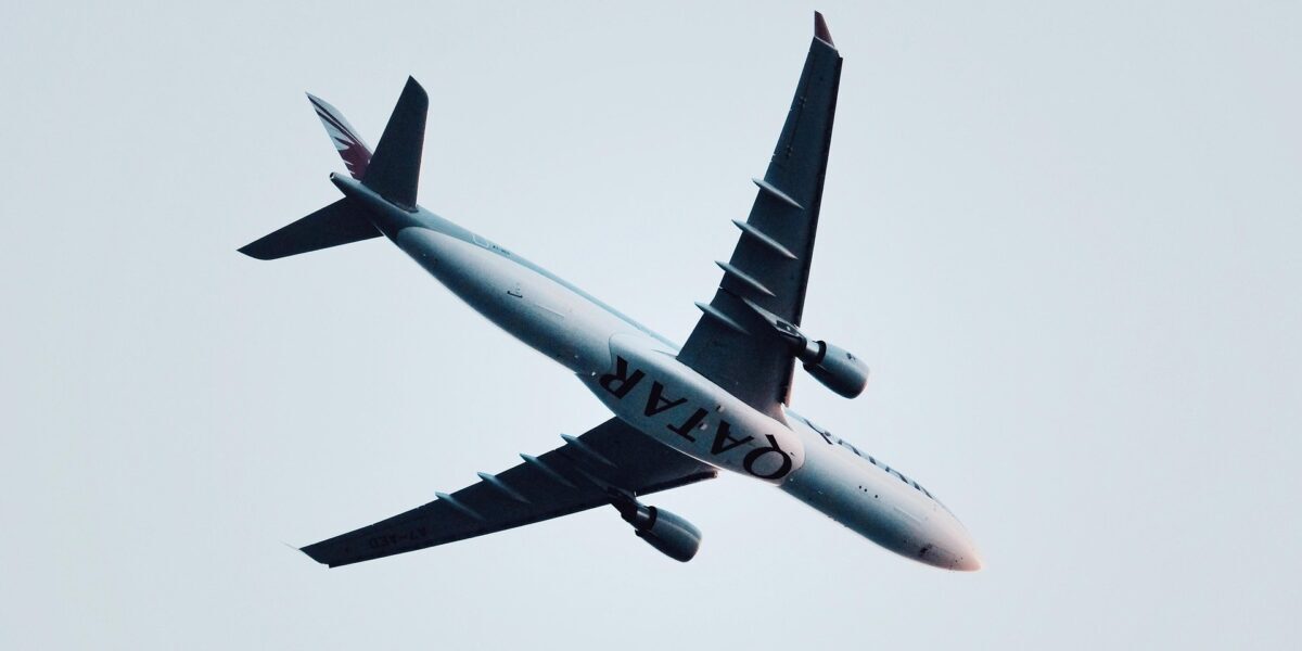 Qatar Airways aircraft flying overhead in clear sky