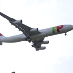 TAP Air Portugal aircraft flying low on final approach with landing gear extended.