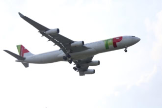 TAP Air Portugal aircraft flying low on final approach with landing gear extended.