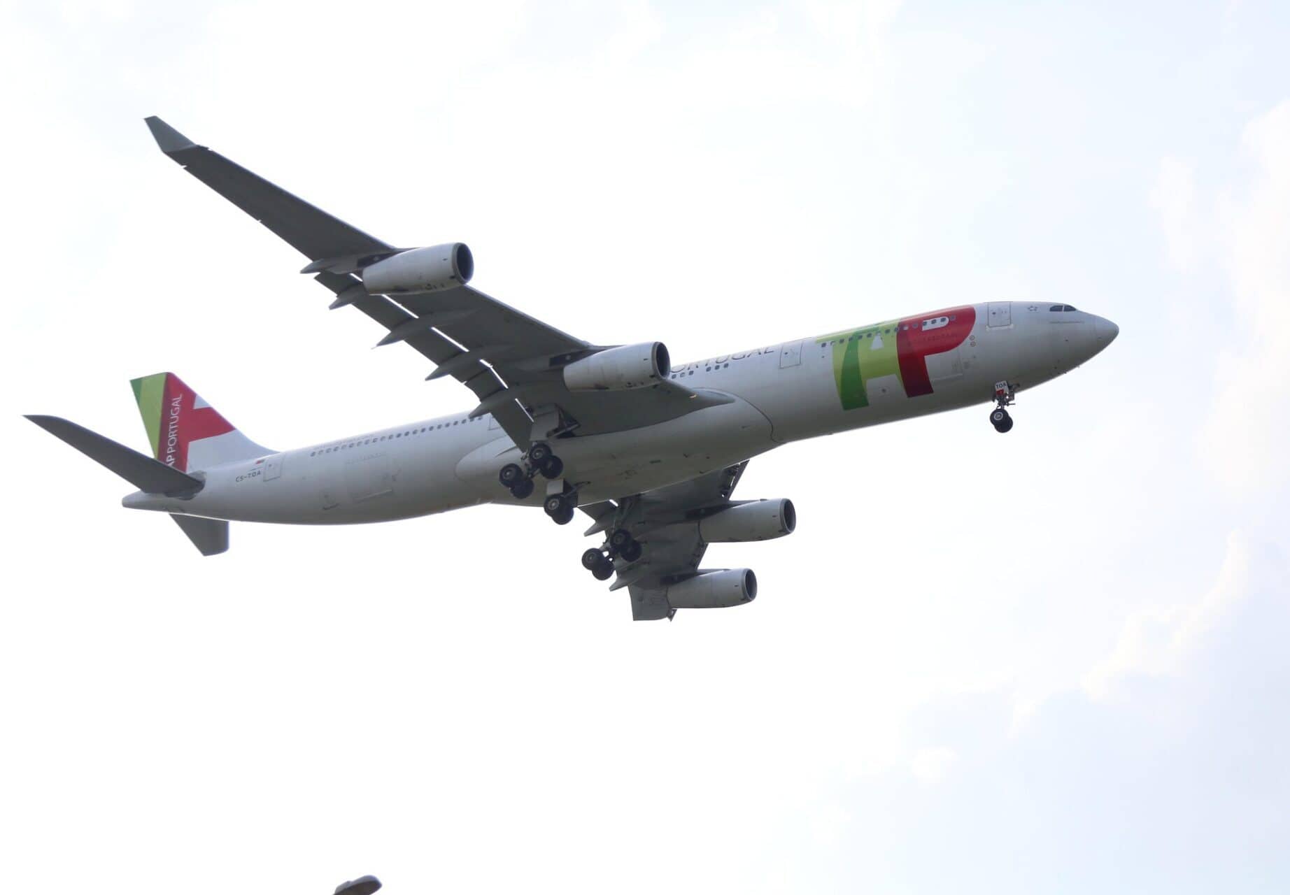 TAP Air Portugal aircraft flying low on final approach with landing gear extended.