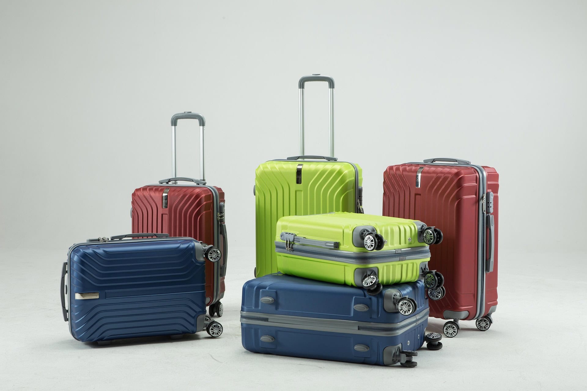 Hard-shell suitcases in blue, red, and lime green arranged together, showing different sizes of carry-on and cabin luggage.