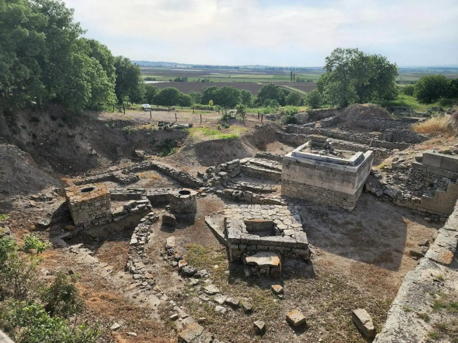 Stone ruins and excavation trenches at the archaeological site of ancient Troy in Turkey.