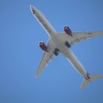 Virgin Atlantic aircraft flying overhead against a clear blue sky