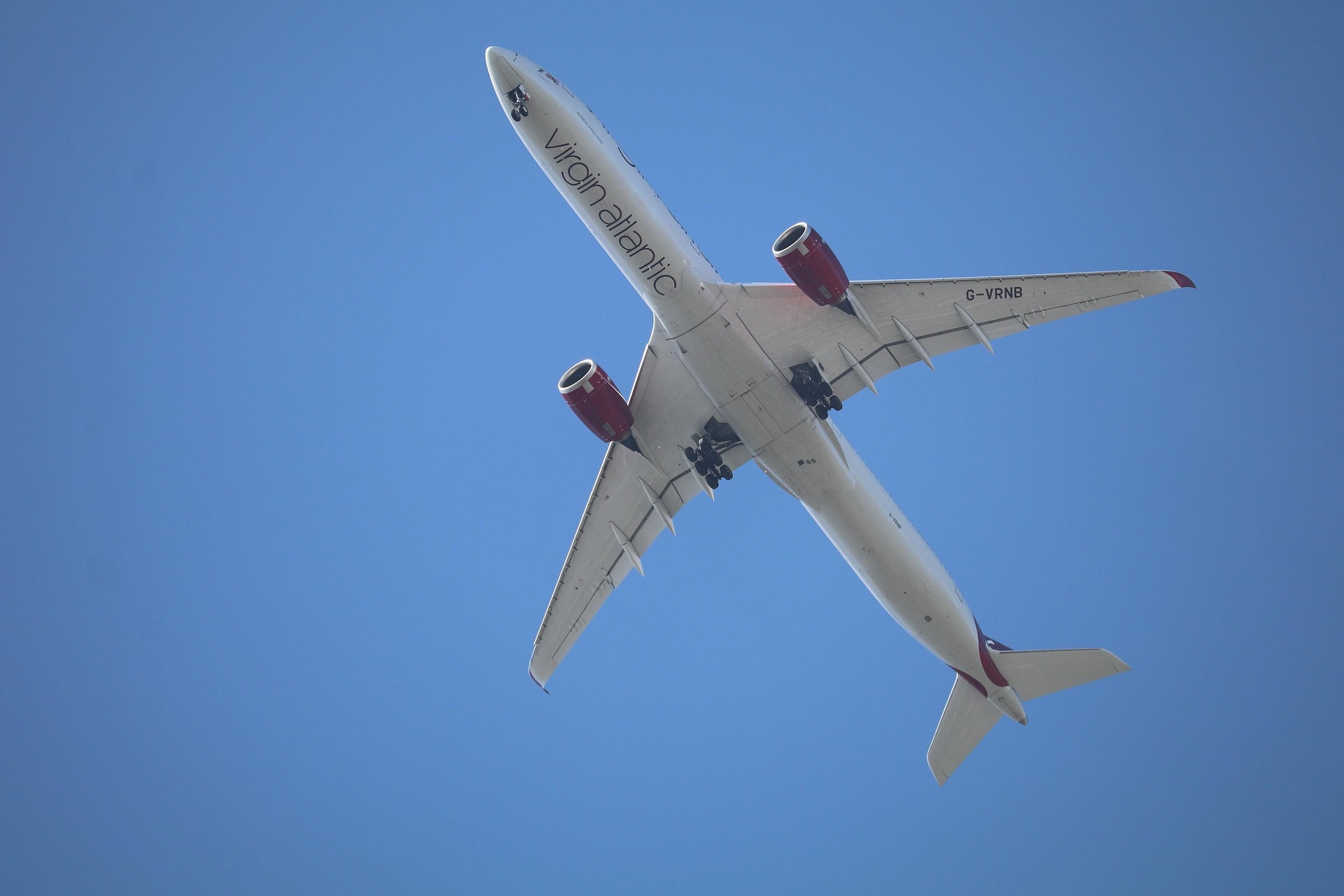 Virgin Atlantic aircraft flying overhead against a clear blue sky