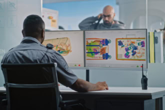 Airport security officer analysing carry-on luggage using X-ray baggage scanner at airport security checkpoint