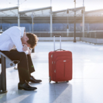 Passenger sitting with luggage during airport strike disruption