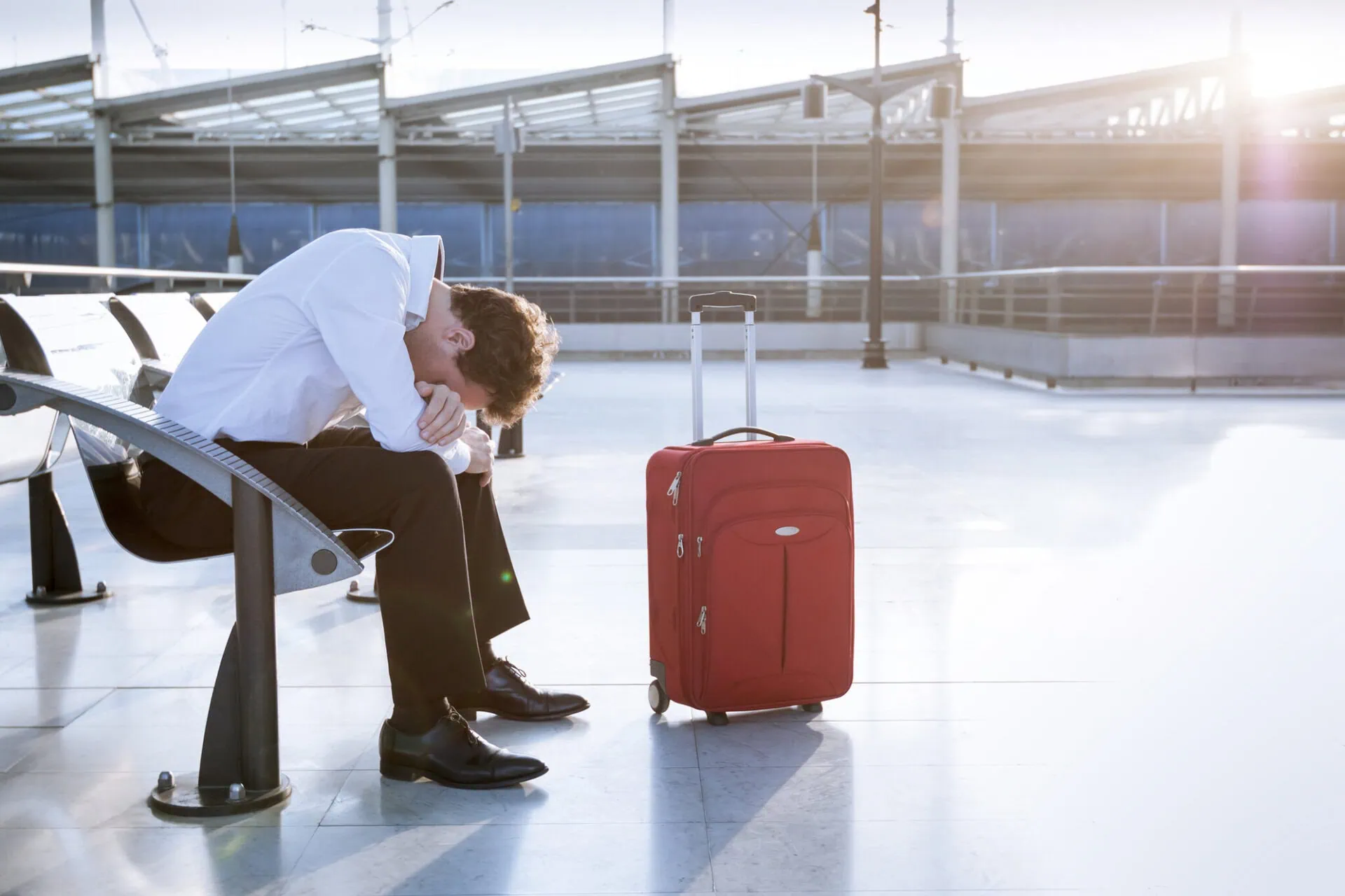 Passenger sitting with luggage during airport strike disruption