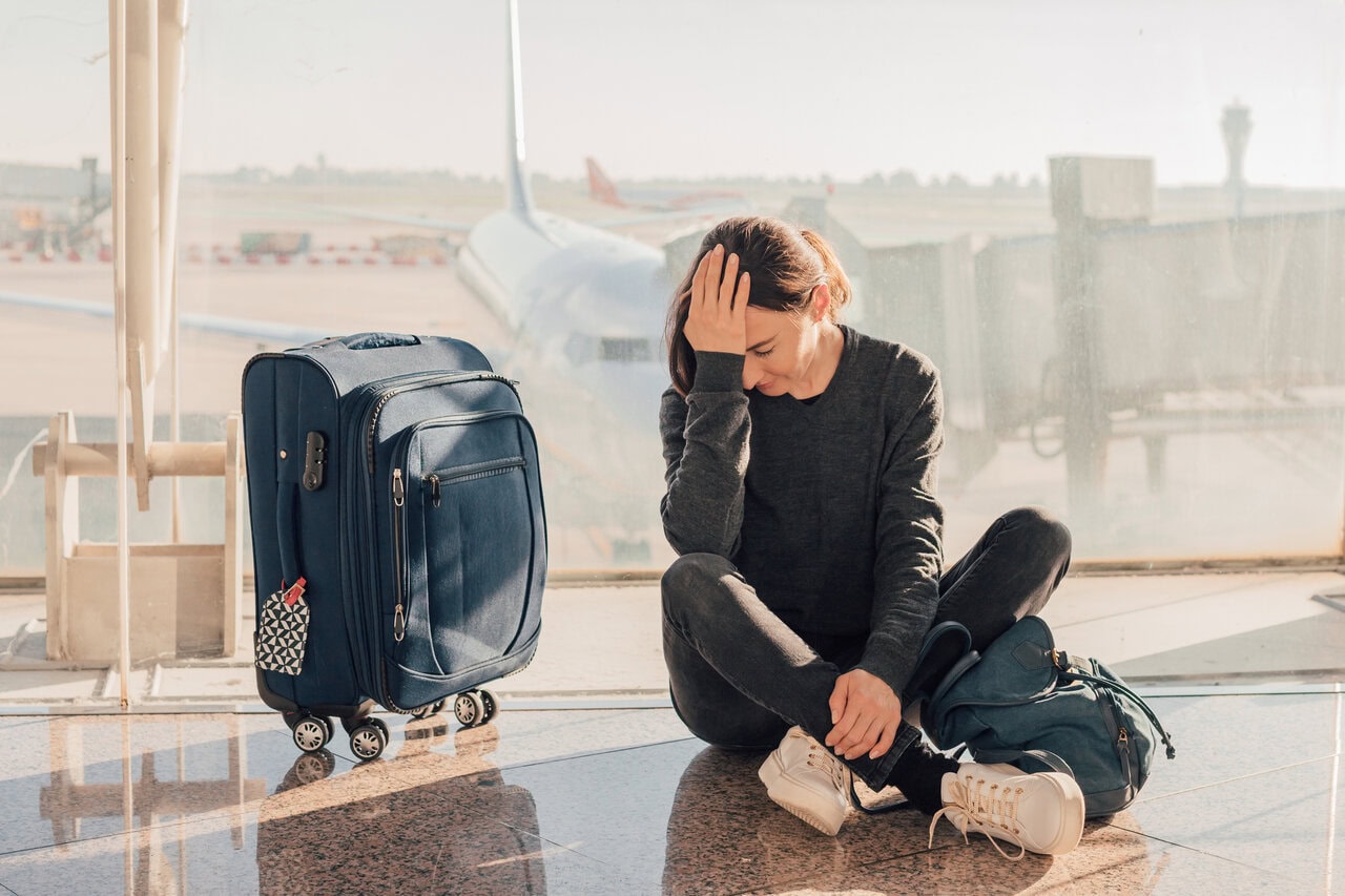 Passenger sitting on airport floor after being denied boarding for a flight