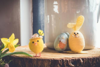 Easter decorations with chick, bunny and eggs beside spring flowers
