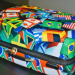 Suitcase covered in international flags representing global travel and lost luggage issues