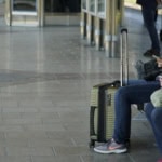 Luggage storage travel – travellers sitting with suitcases at a train station