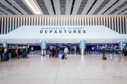 Manchester Airport departures hall showing travellers preparing for flights across Europe