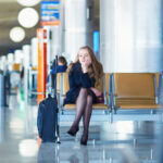 Passenger sitting in an airport terminal with luggage after missing a connecting flight