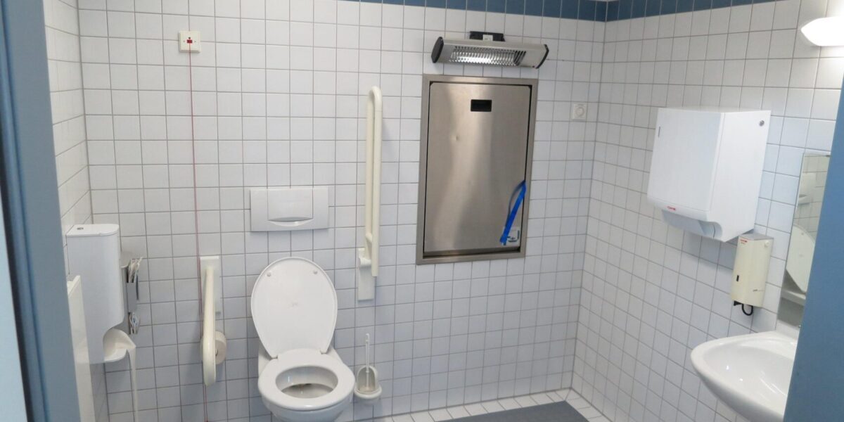 Accessible public toilet with wheelchair grab rails and baby changing station