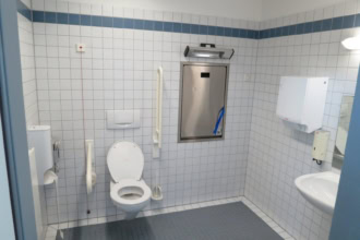 Accessible public toilet with wheelchair grab rails and baby changing station