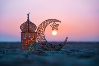 Travel during Ramadan: traditional lantern and crescent moon at sunset