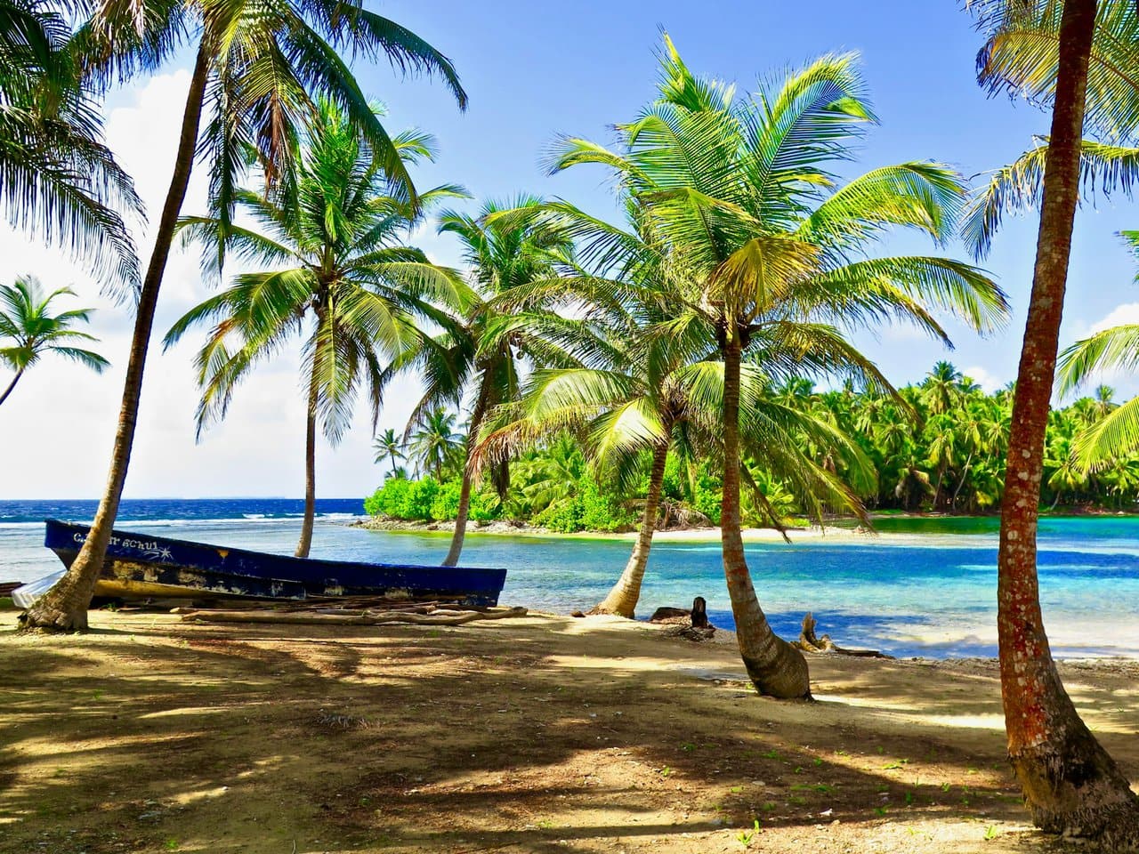 San Blas Islands Panama tropical beach with palm trees and wooden boat