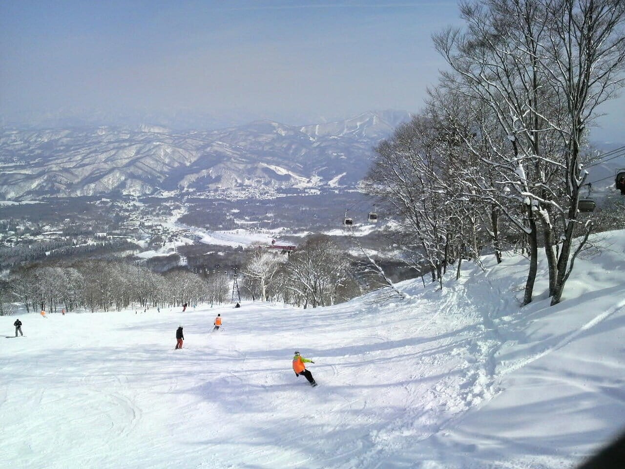 Skiing in Japan with wide groomed slope and mountain views in the background
