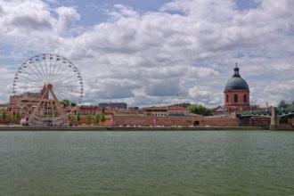 Toulouse riverfront with Ferris wheel and historic buildings near Garonne River