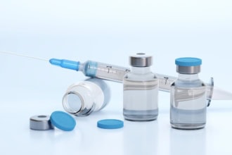 Travel vaccinations with syringe and vaccine vials on a clean medical background