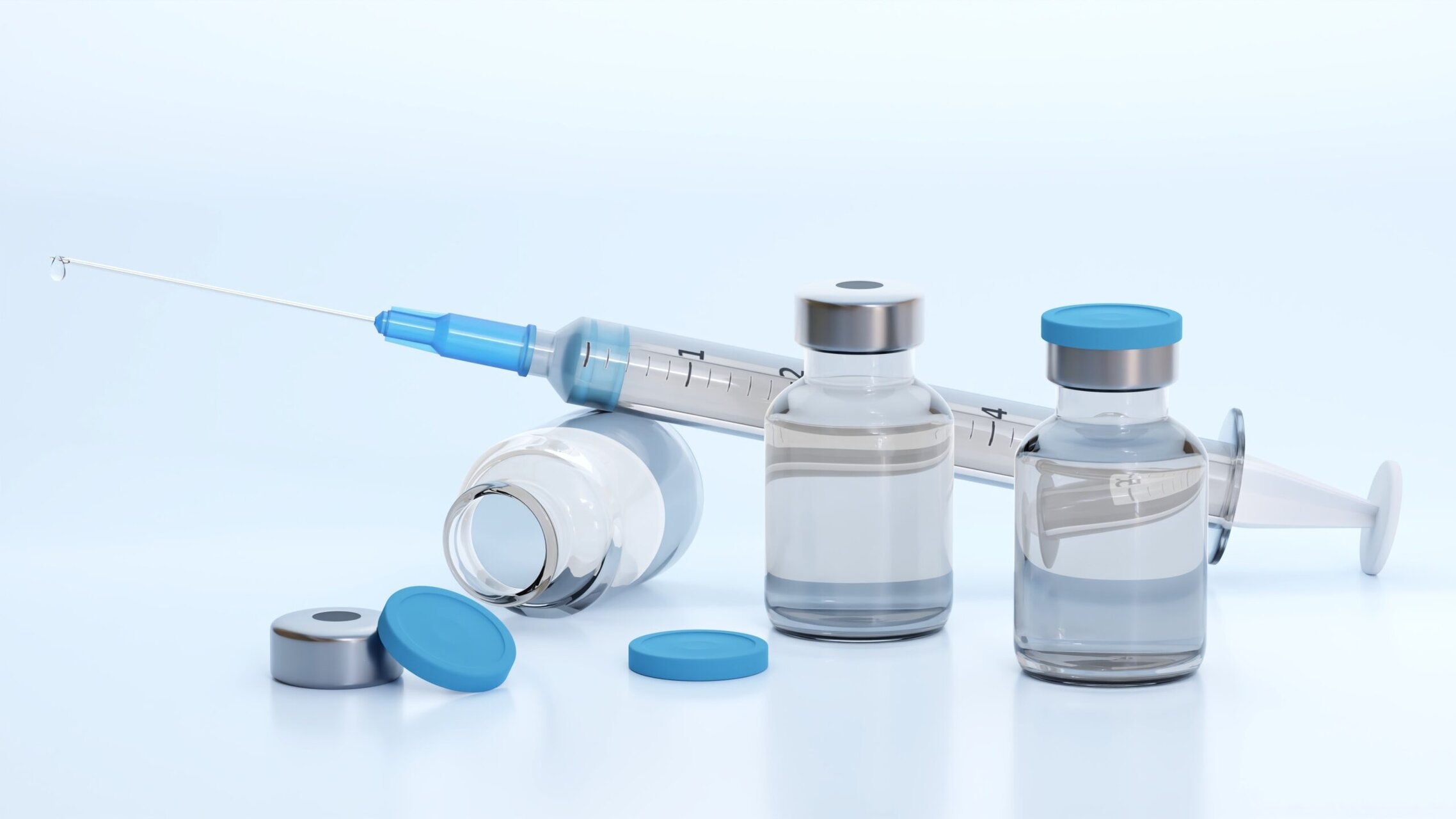 Travel vaccinations with syringe and vaccine vials on a clean medical background