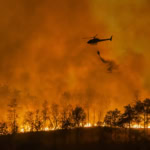 Helicopter battling wildfire as forest burns during emergency response