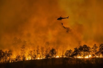 Helicopter battling wildfire as forest burns during emergency response