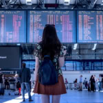 Passenger looking at airport departure board showing delayed flights