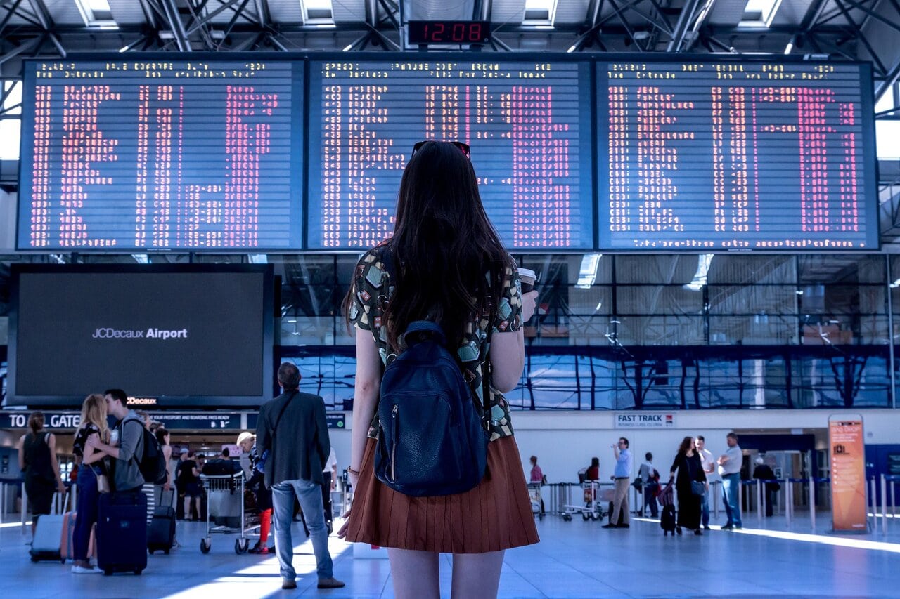 Passenger looking at airport departure board showing delayed flights