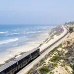 Amtrak train travelling along the Pacific coastline on a coastal rail route in California