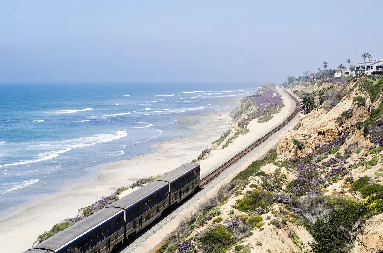 Amtrak train travelling along the Pacific coastline on a coastal rail route in California